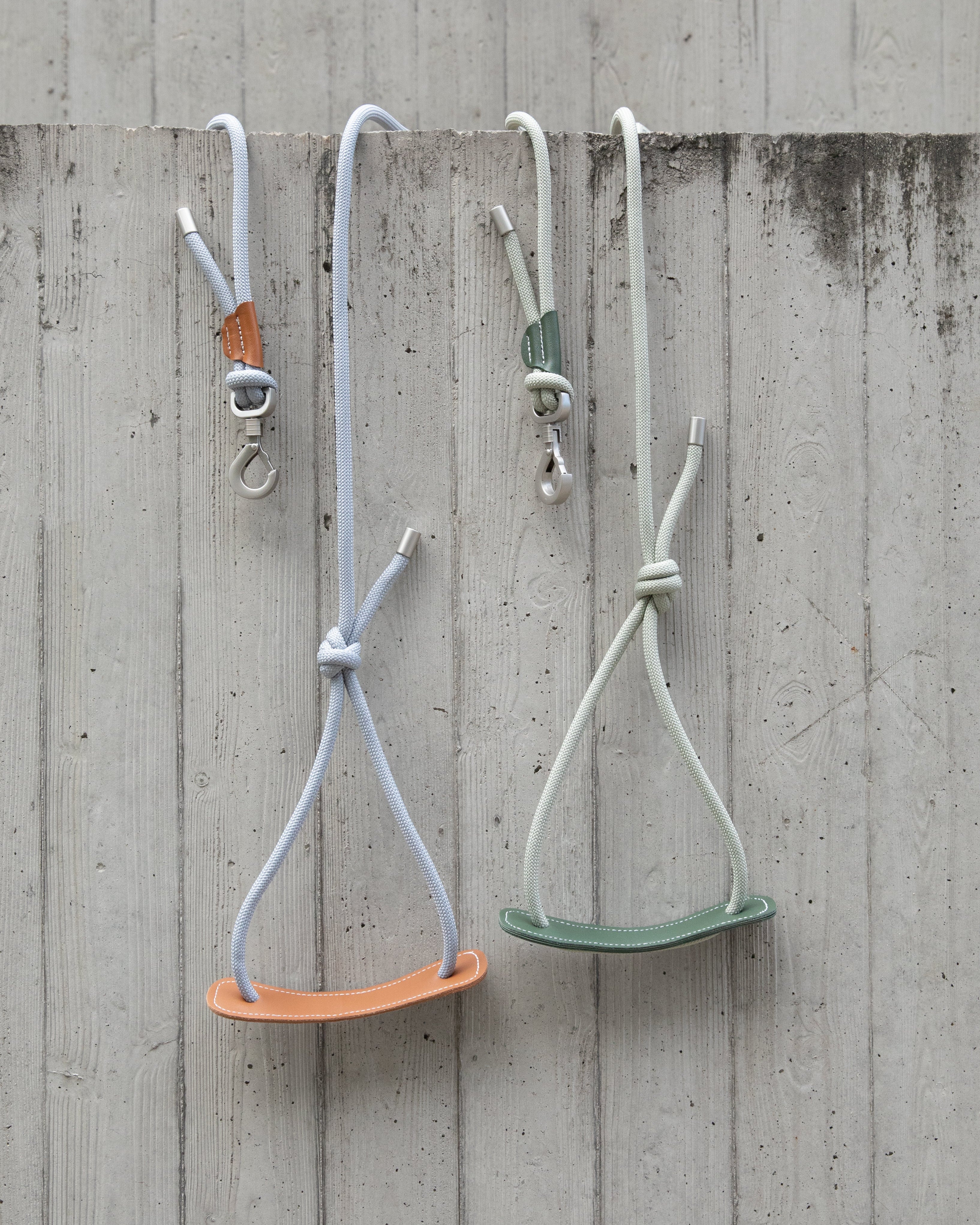 Two dog's leashes hanging on a concrete wall.