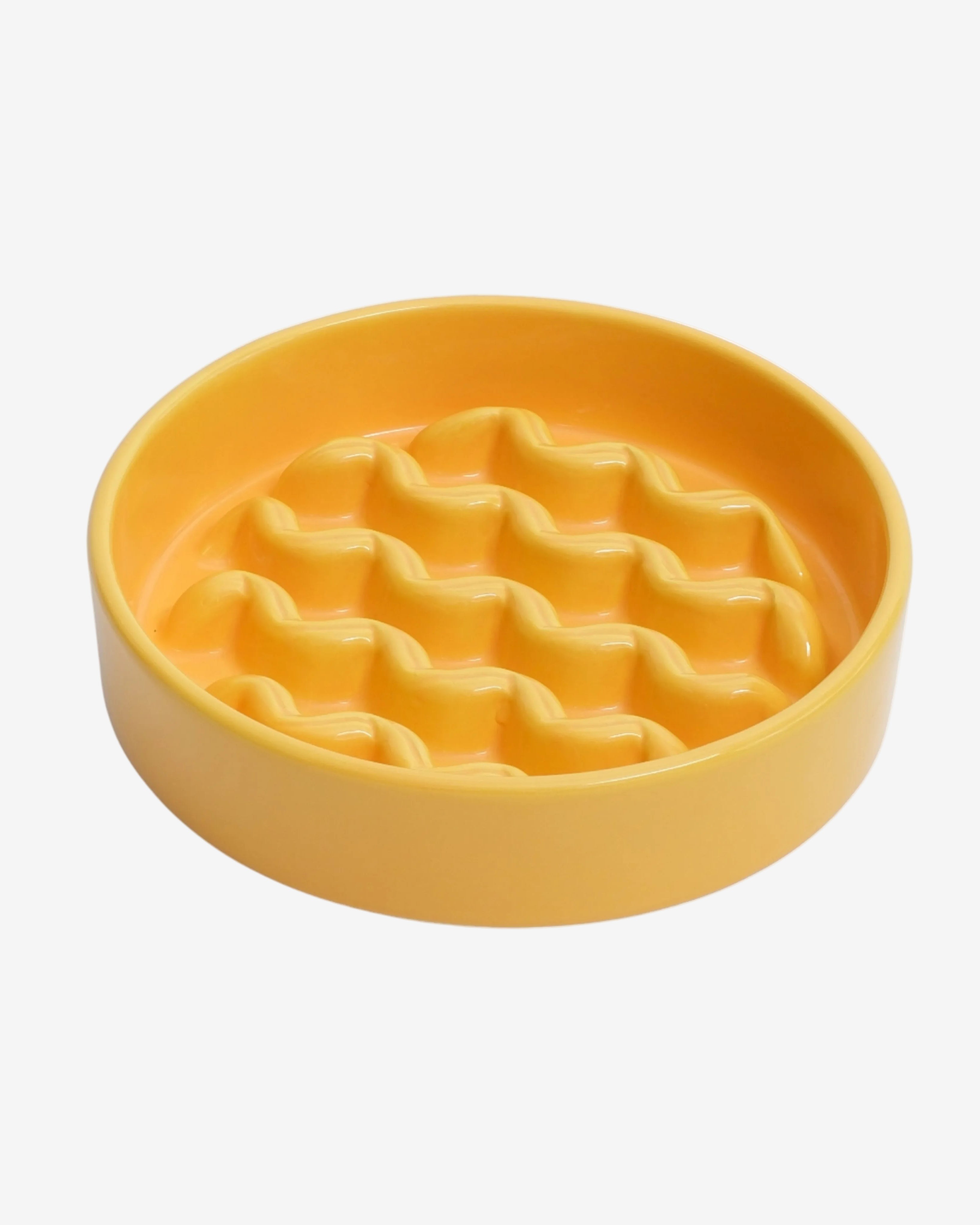 Yellow slow feeder dog bowl with macroni pattern on a white background