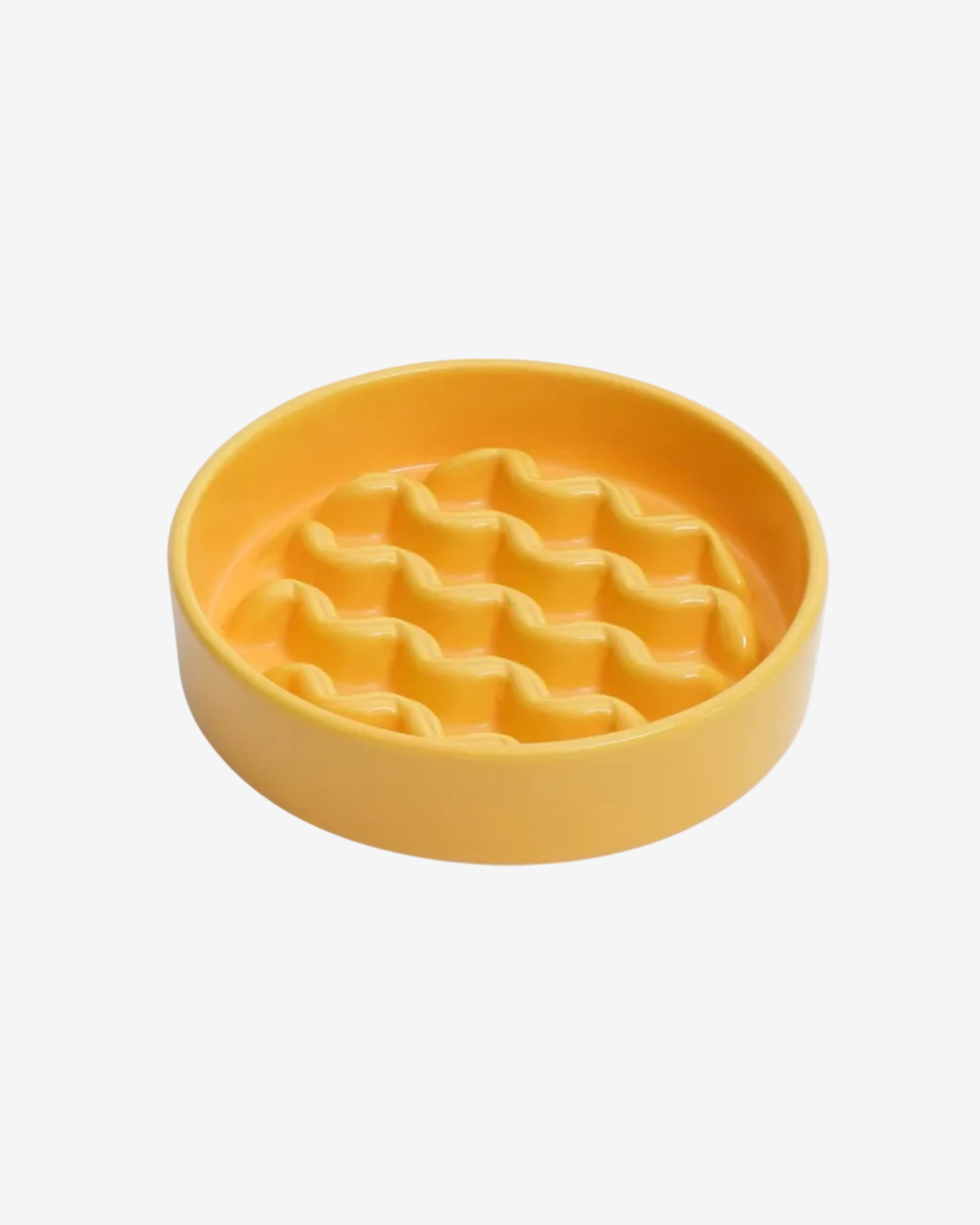 Yellow slow feeder dog bowl with macroni pattern on a white background