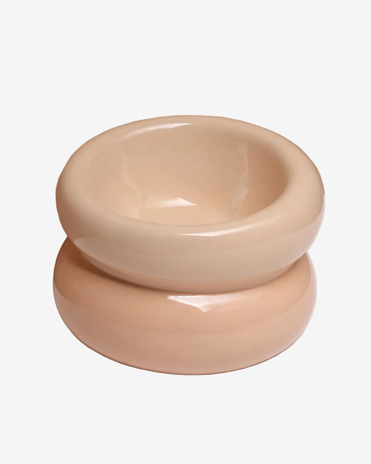 Two beige ceramic bowls stacked on a white surface with a beige background