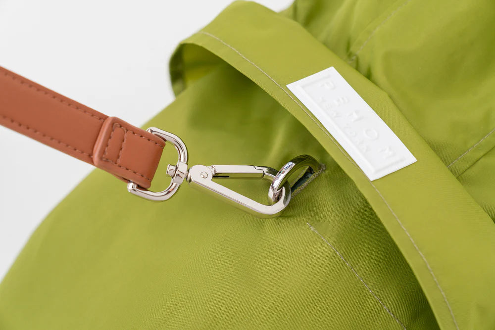 Green bag with a brown strap and silver clasp on a white background