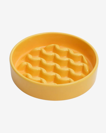 Yellow slow feeder dog bowl with macroni pattern on a white background