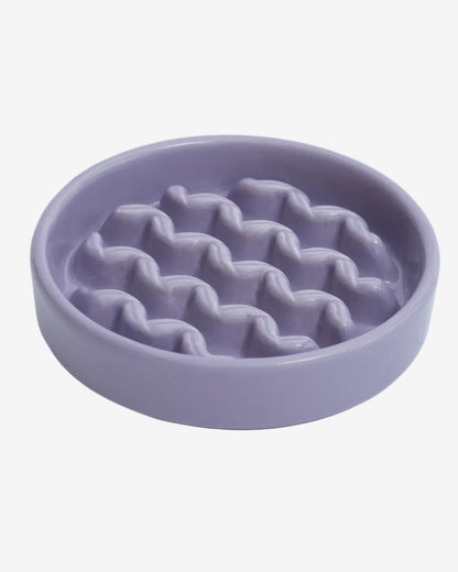 Purple macroni-shaped ceramic slow feeder dog bowl on a white background